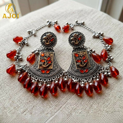 Oxidised two-tone floral earring with ruby red crystal drop, front view