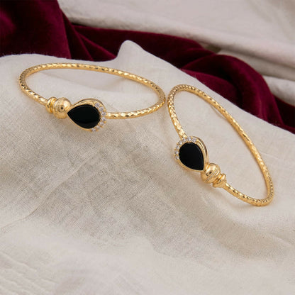 Side view of gold plated black stone kada bracelet pair