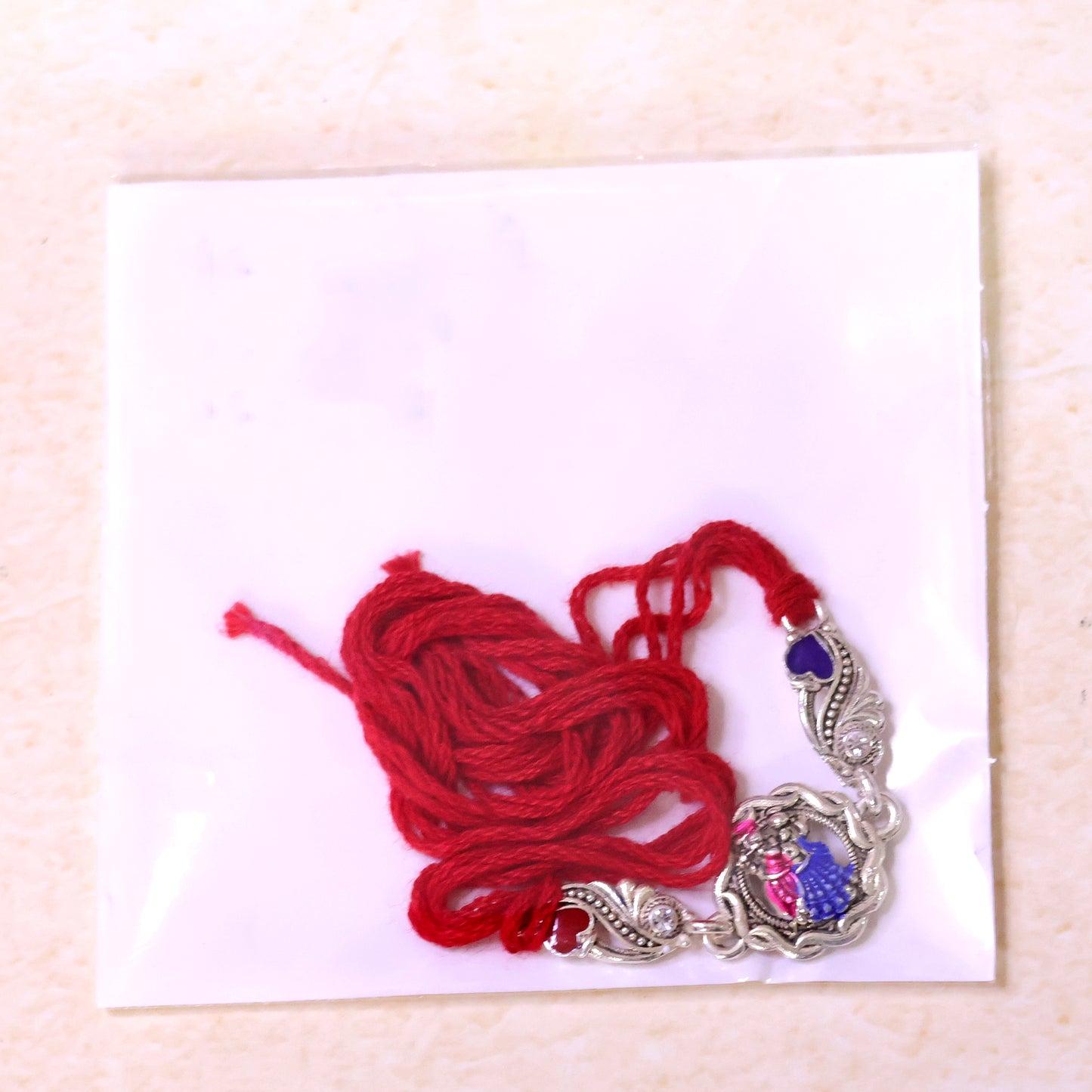 Silver-Toned Radha Krishna Rakhi with Colorful Enamel, Crystal Accents & Designer Red Thread