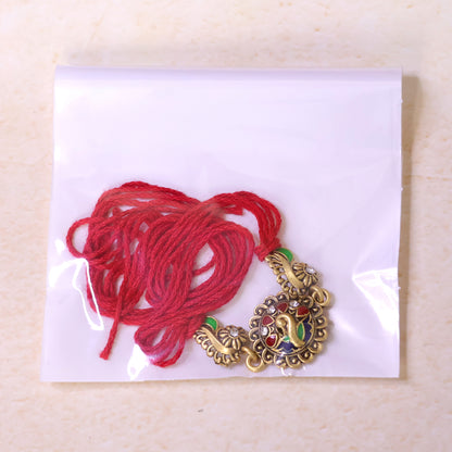 Antique Gold-Toned Peacock Rakhi with Multicolor Enamel, Crystal Accents & Red Thread