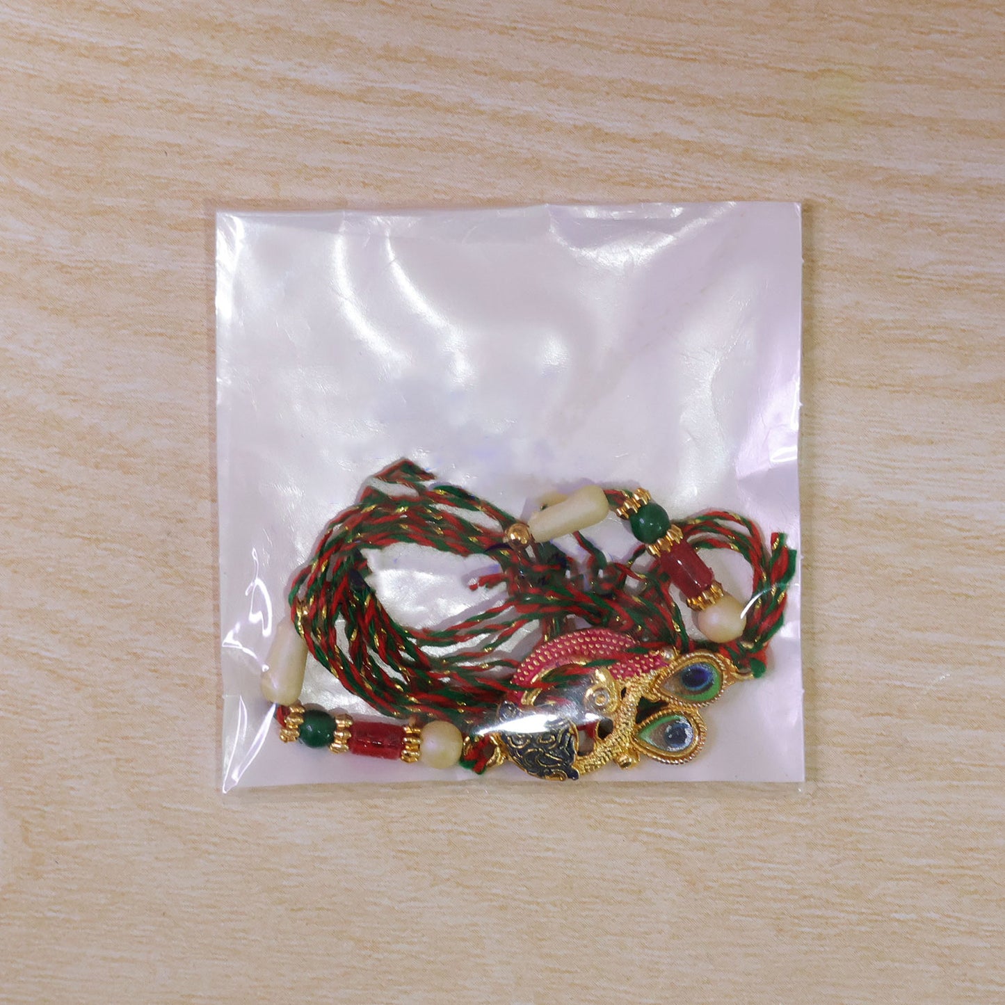 Peacock Rakhi Set with Red Thread, Gold Beads and Meenakari Accent Design