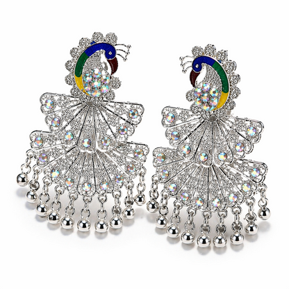 Two ornate silver peacock-shaped earrings with vibrant enamel and numerous clear faceted stones on a white background.