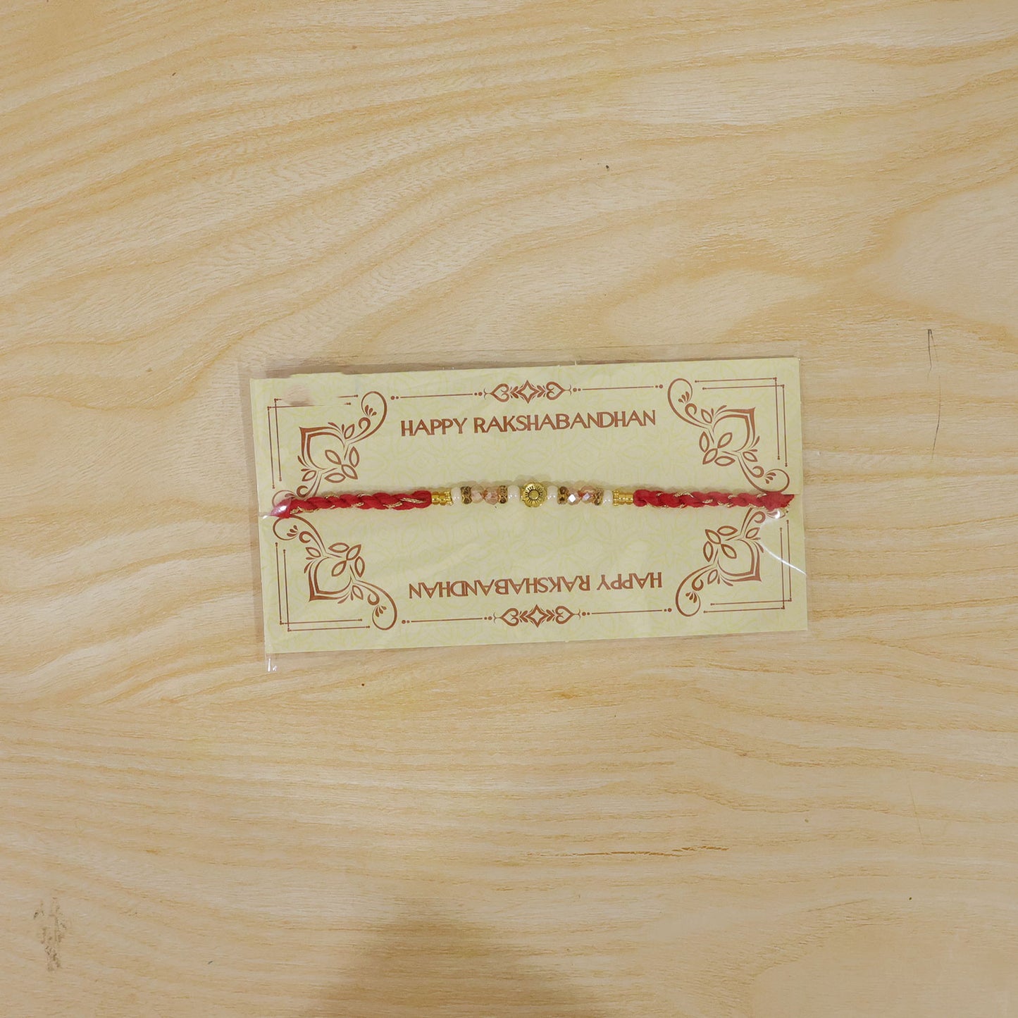 Red Thread Rakhi with Pearls, Crystal Beads and a Gold Flower Charm
