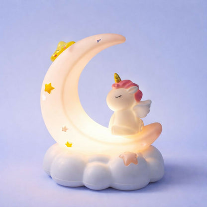 The unicorn crescent moon night light, emitting a warm glow, rests on a light blue backdrop.