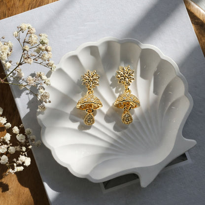 Close-up of sunburst floral jhumka earrings in gold finish with crystal accents