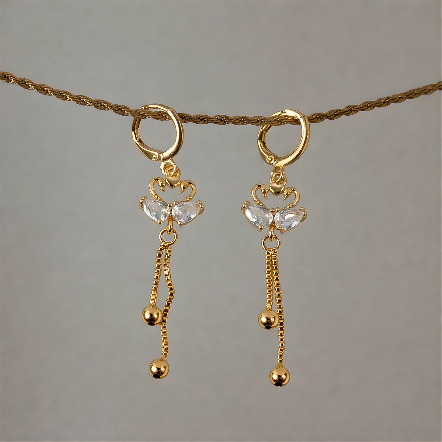 Side view of swan dangle earrings showcasing huggie hoop and hanging chains
