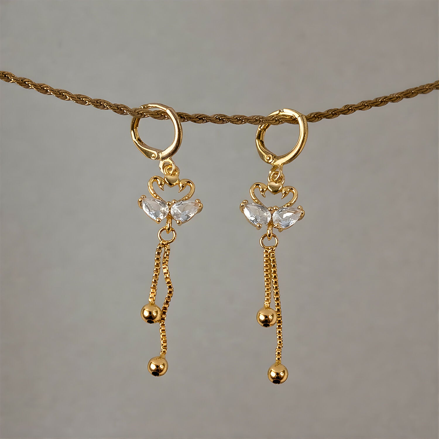 Side view of swan dangle earrings showcasing huggie hoop and hanging chains