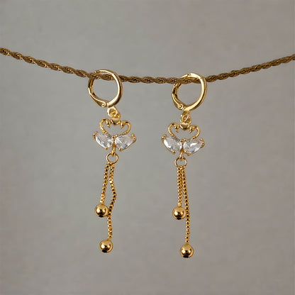 Side view of swan dangle earrings showcasing huggie hoop and hanging chains