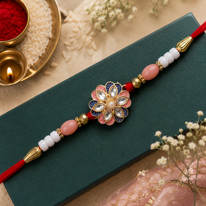 A red thread with pink and white beads, gold accents, and a central floral charm with pink, blue, and clear stones, rests on