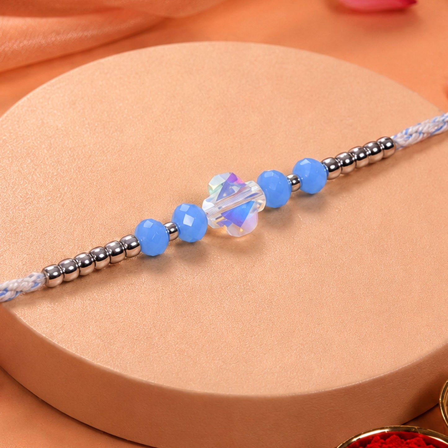 Blue Crystal Bead Rakhi with Round Stone Centre, Silver Highlights and Red Thread