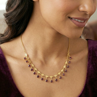 Gold plated necklace with decorative red stone drops on white background
