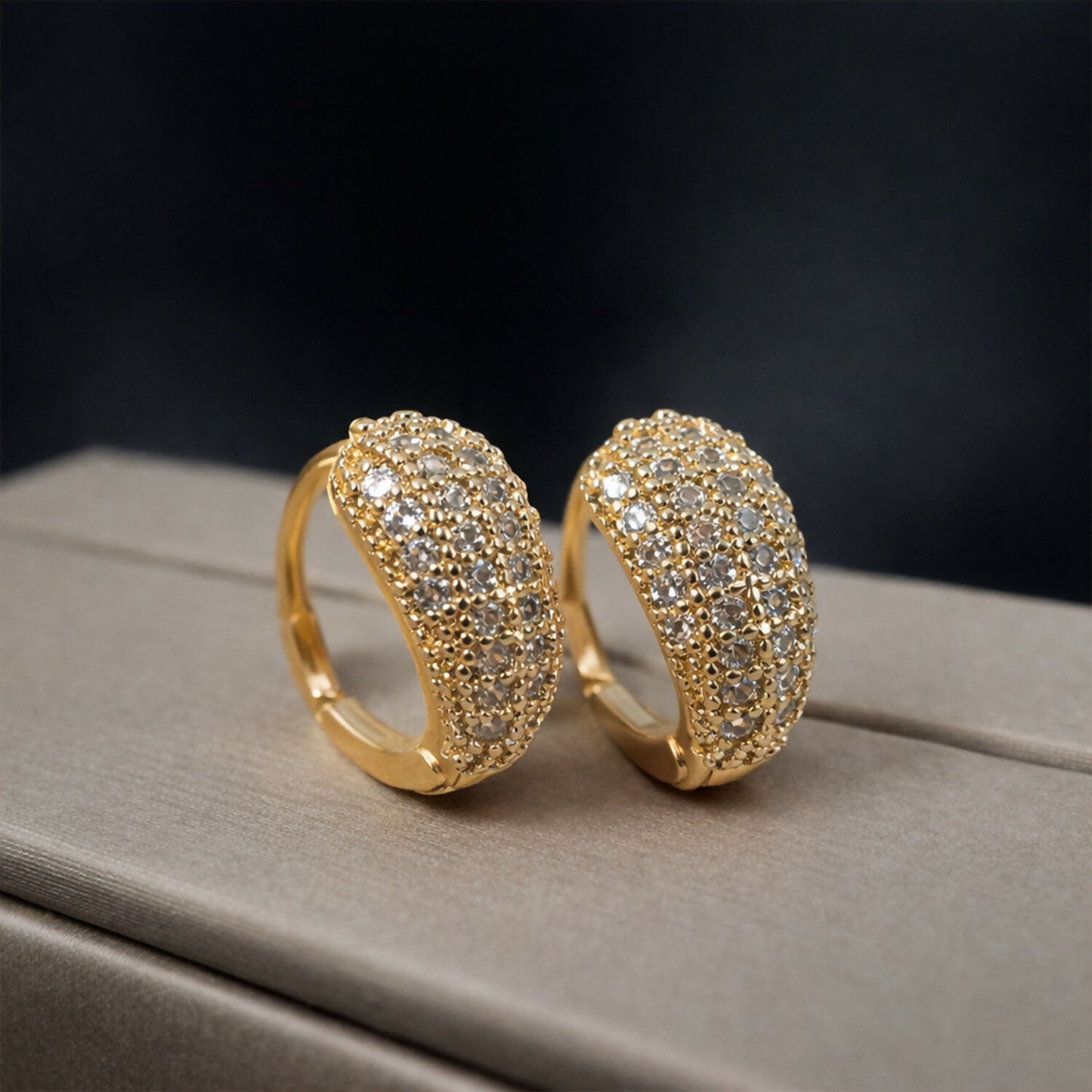 Wide textured crystal huggie hoops with gold finish sparkling in light