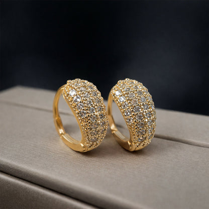 Wide textured crystal huggie hoops with gold finish sparkling in light