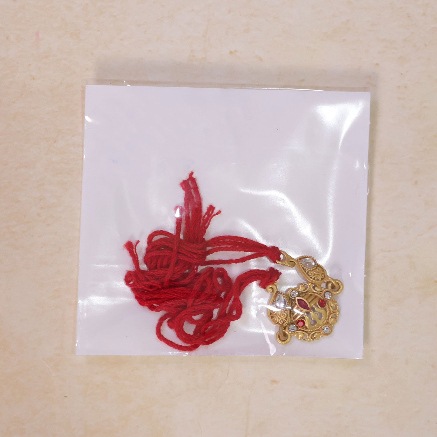 Gold-Toned Trishul Rakhi with Red Stones, Clear Crystal Accents & Designer Red Thread