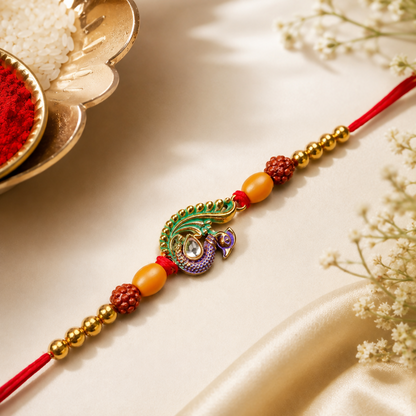 A decorative thread featuring a peacock charm with green and purple enamel, flanked by golden and reddish-brown beads, rests