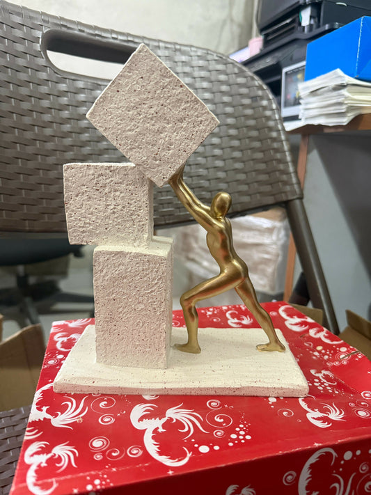 Abstract human figure pushing block sculpture with metallic finish – front view