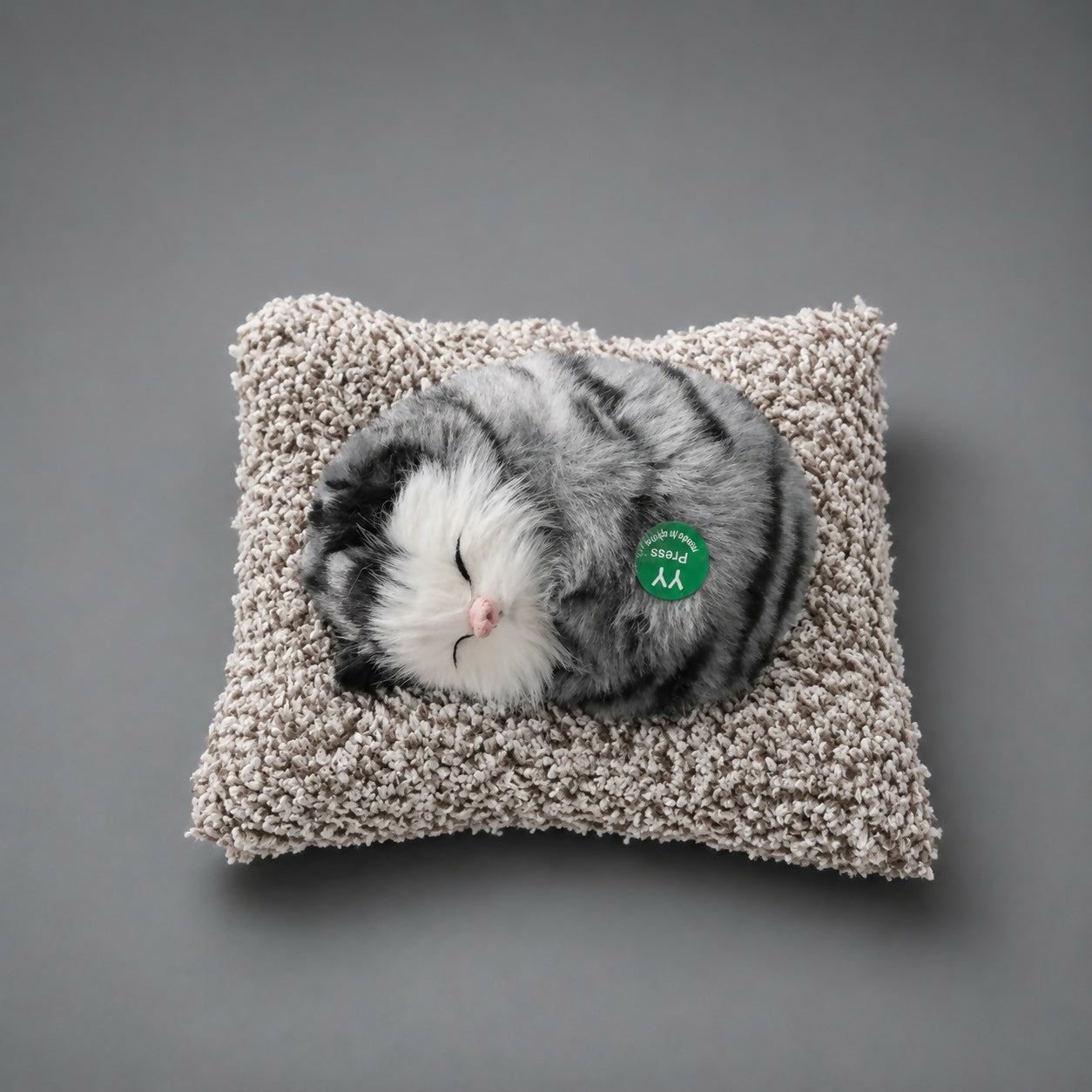 Side view of sleeping cat plush toy on cushion