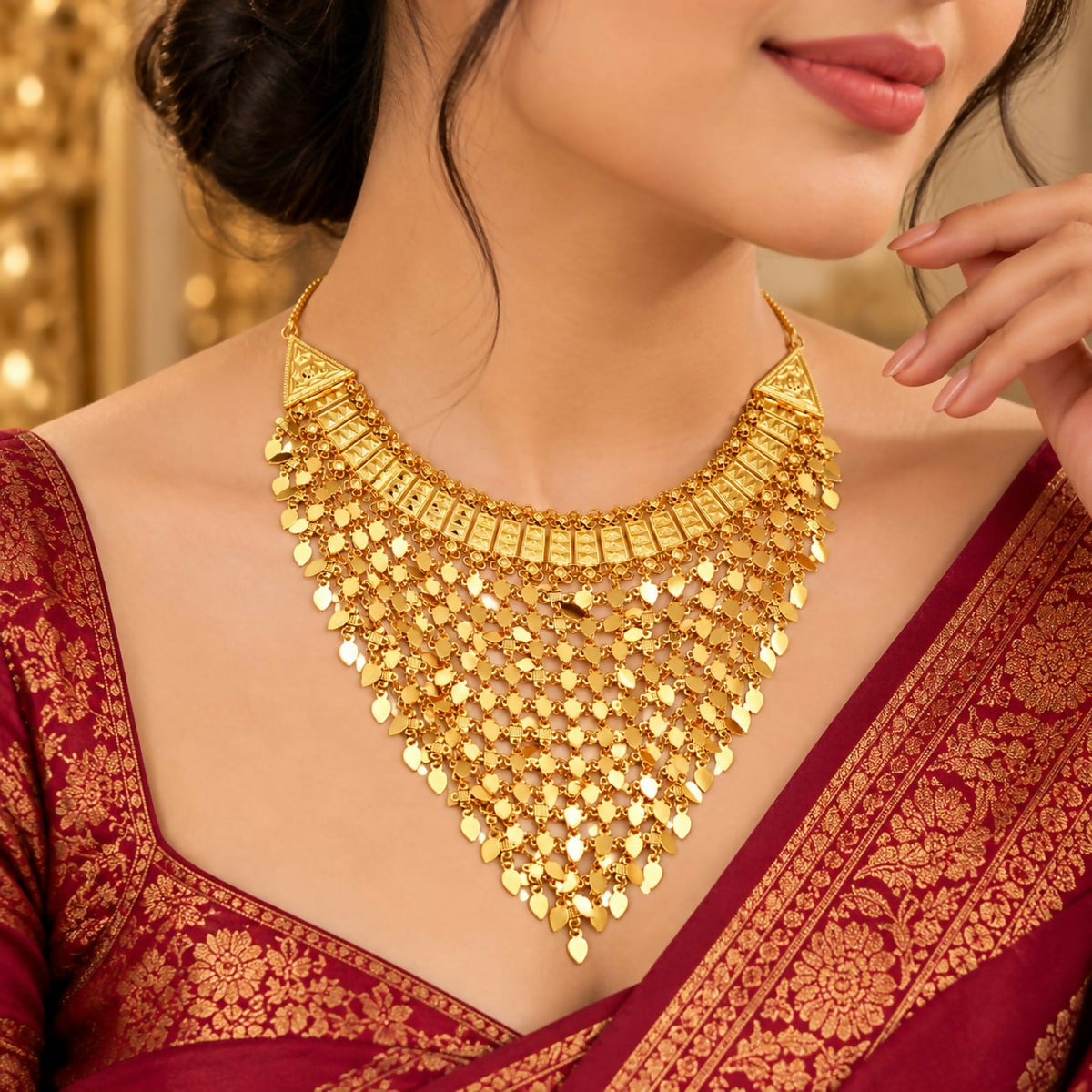 A woman wears a large, ornate gold necklace with many small, dangling leaf-shaped pieces over a red patterned garment.