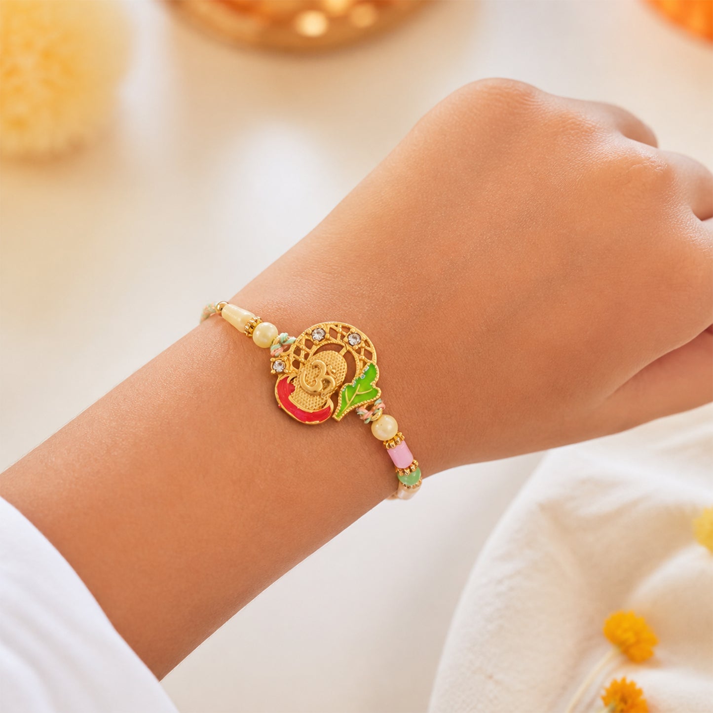 Textured Gold Om Pendant Rakhi with Leaf Accent and Pearl Beads