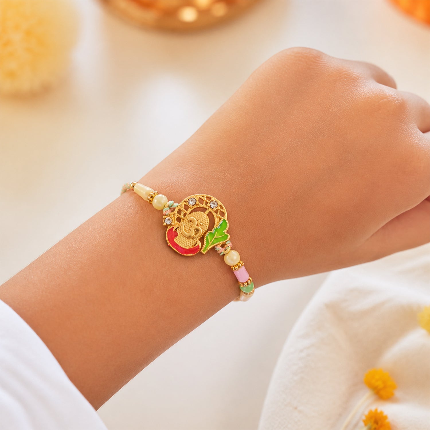 Textured Gold Om Pendant Rakhi with Leaf Accent and Pearl Beads