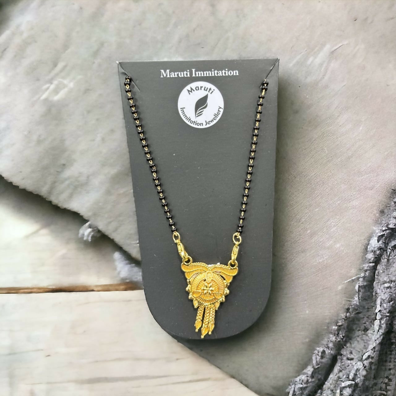 This stunning pendant, made of durable imitation metal and finished in gold tone, features detailed craftsmanship and a regal tassel drop.