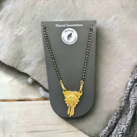 This stunning pendant, made of durable imitation metal and finished in gold tone, features detailed craftsmanship and a regal tassel drop.