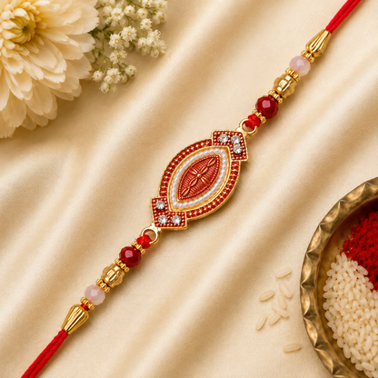 A red and gold bracelet with an oval centerpiece, adorned with white beads and red stones, lies on a golden silk cloth with