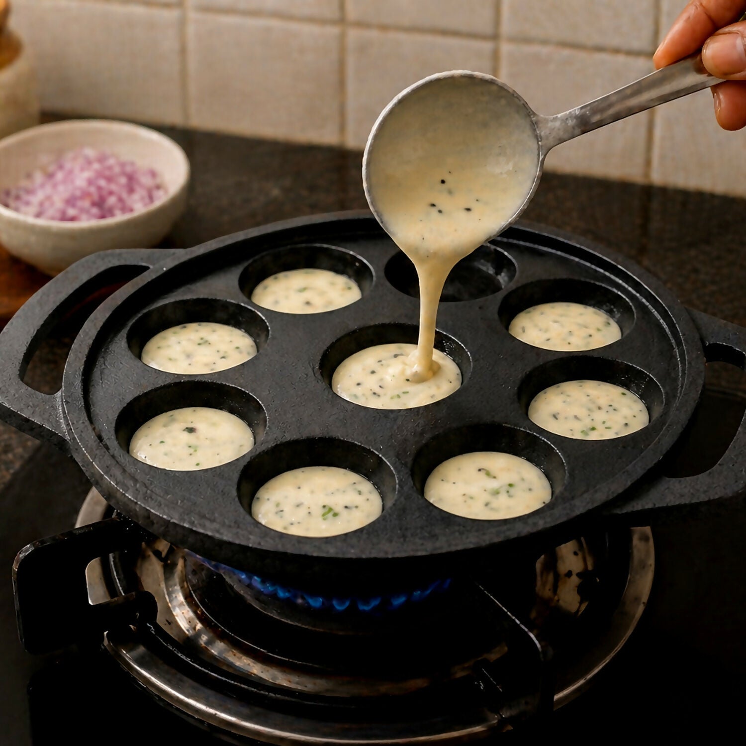 Cast iron 9 cavity appam patra showing multiple round cavities