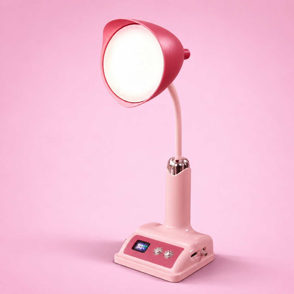 A pink desk lamp with a glowing circular light and a small screen on its base is centered on a light pink surface.