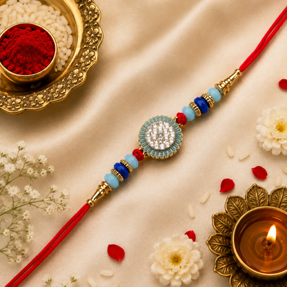 The red thread bracelet with its crystal-studded medallion and blue beads is displayed on a light gold satin fabric,
