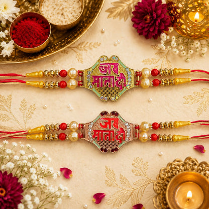 Two ornate bracelets with "Jai Mata Di" in Hindi, one green and one red, surrounded by pearls and beads on a beige cloth.