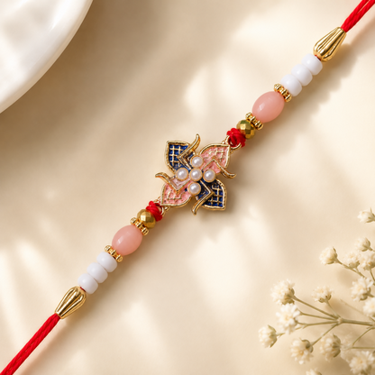 A red and white beaded bracelet with a central pink and blue floral charm is shown on a light, textured background with a