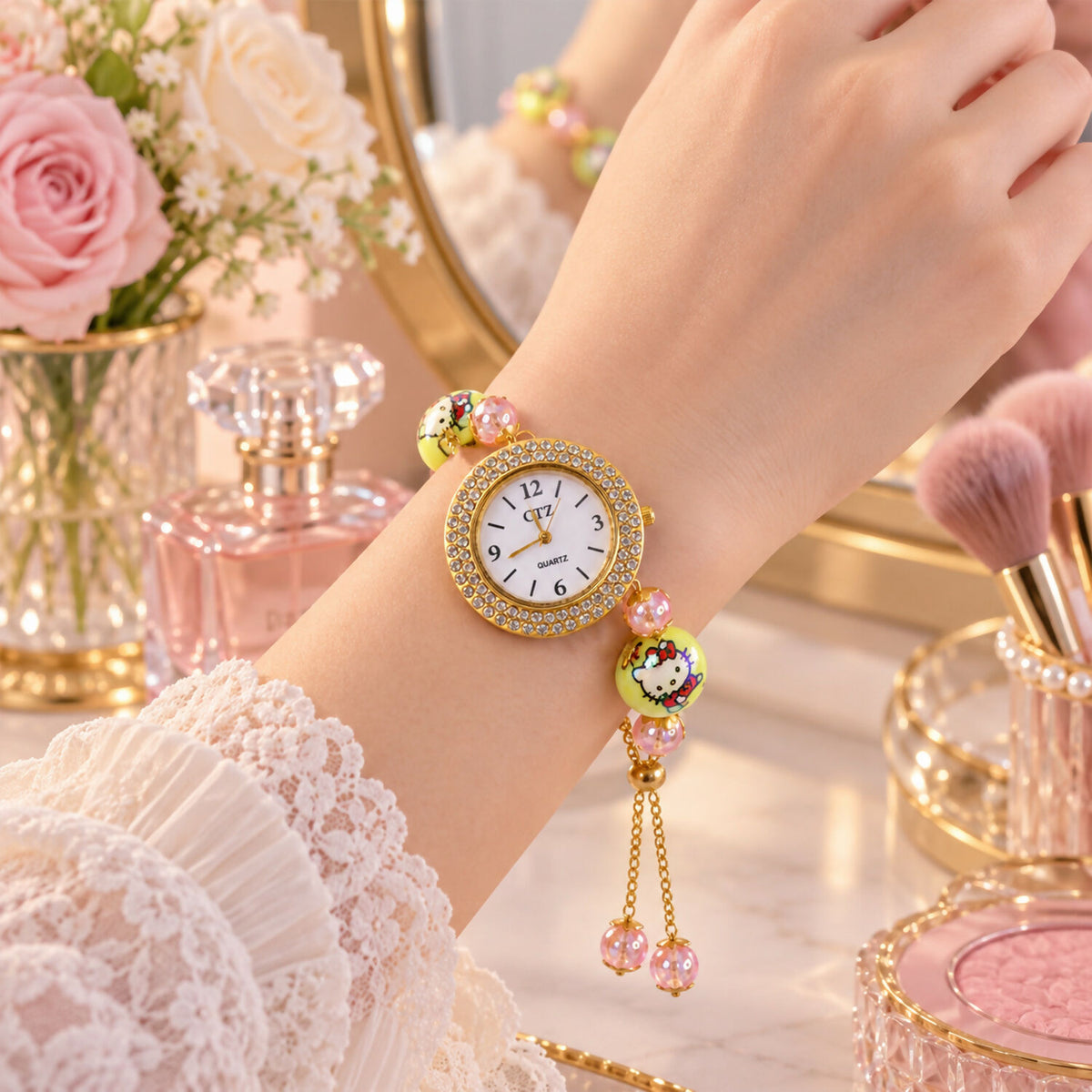 A woman's wrist displays a gold-tone bracelet watch with a rhinestone dial, two yellow cartoon character beads, and smaller
