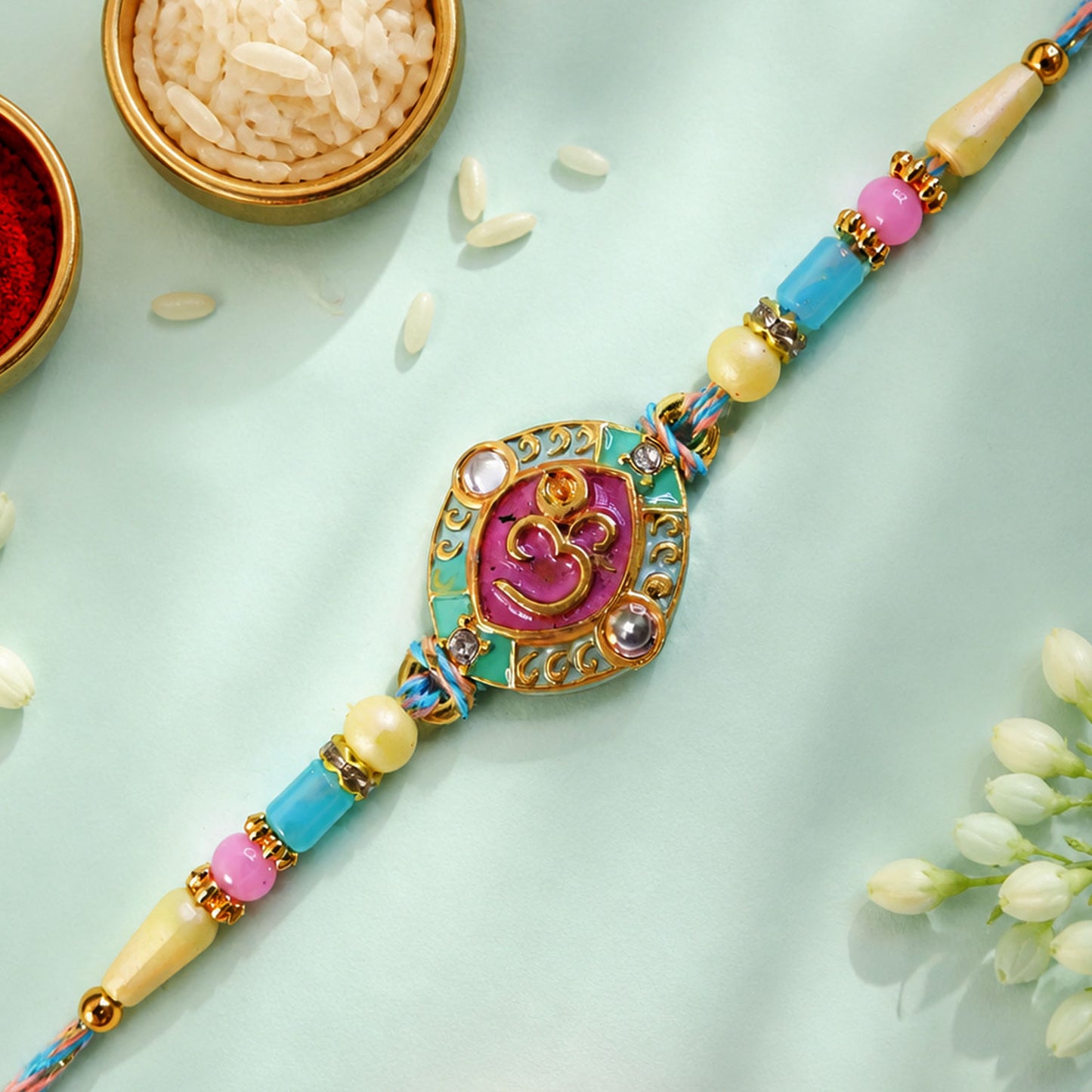 Turquoise Om Pendant Rakhi with Pink Kundan and Pastel Beads