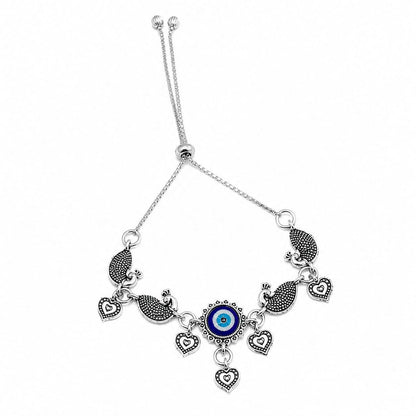 The oxidized silver evil eye peacock charm bracelet with heart dangles is displayed on a plain white background.