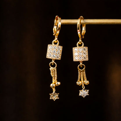 Side view of gold finish square drop earrings featuring star-shaped charm and sparkling stones