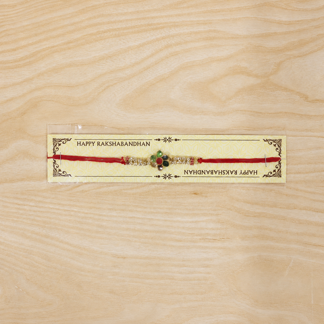 Tiny Oval Stone Rakhi with Red Thread and Delicate Gold Beads