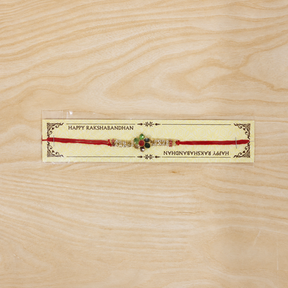 Tiny Oval Stone Rakhi with Red Thread and Delicate Gold Beads