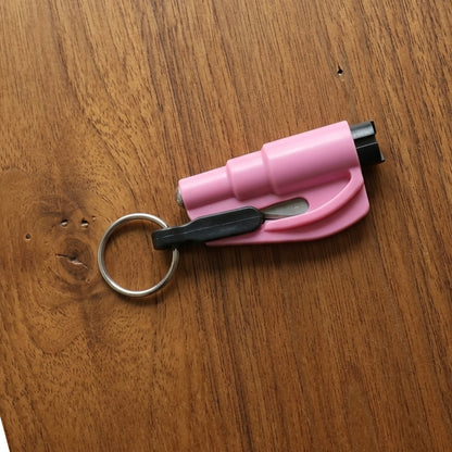 A pink emergency car window breaker and seat belt cutter tool with a black keychain rests on a warm brown wooden surface.