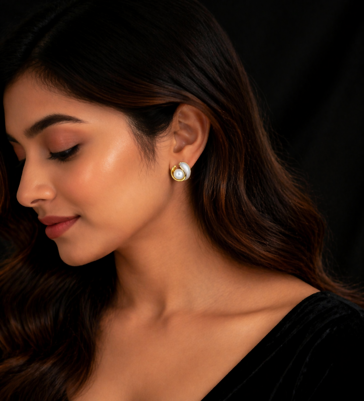 Close-up of gold pearl stud earrings with glossy finish