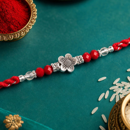 Red Braided Rakhi with Silver Flower Charm and Crystal Bead Accents