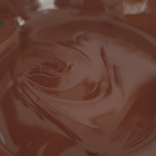 Close-up view of swirling, glossy milk chocolate, showing its rich texture and deep brown color.