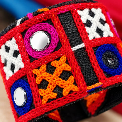 Close-up of the bracelet showing intricate red thread borders, white cross stitching, and circular mirrors.