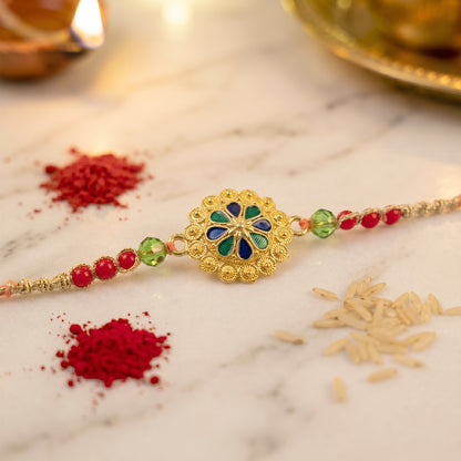 Gold Blue Flower Rakhi with Green Beads and Red Pearl Accents