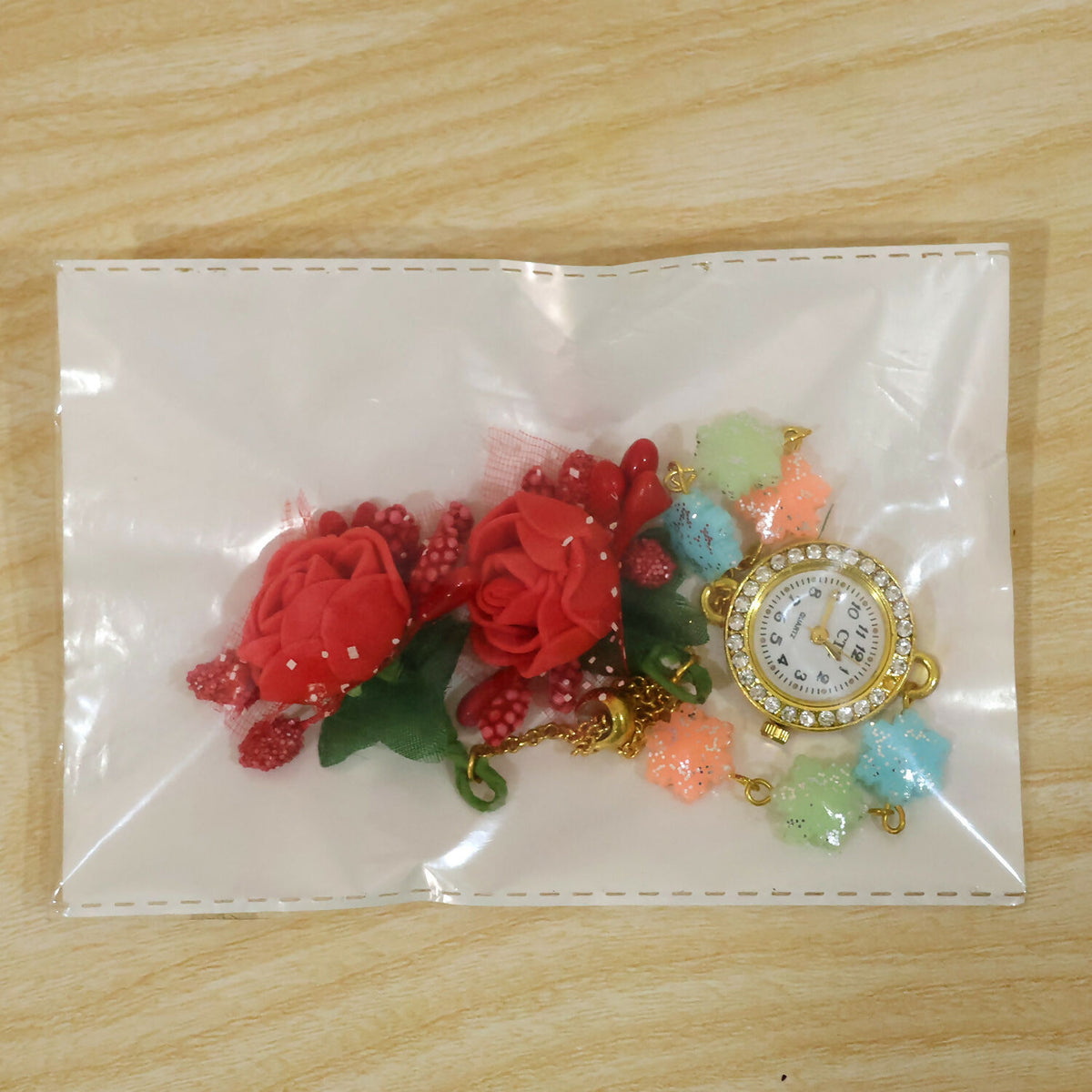 The watch and charms are visible through a clear plastic bag, with the watch face and charms separated.