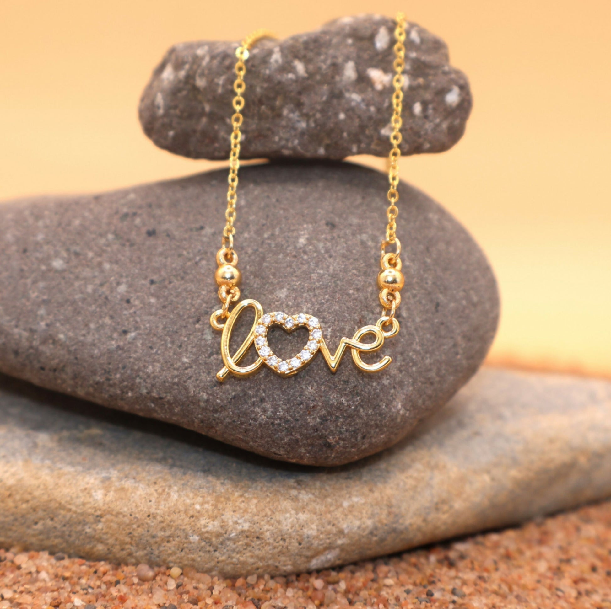 Close-up of gold plated "LOVE" heart necklace pendant adorned with CZ stones for women and girls