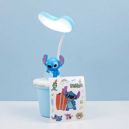A blue Stitch character desk lamp next to a sheet of colorful Stitch themed stickers on a light blue surface.