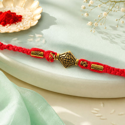 Red Thread Rakhi with an Intricately Detailed Antique Gold Charm