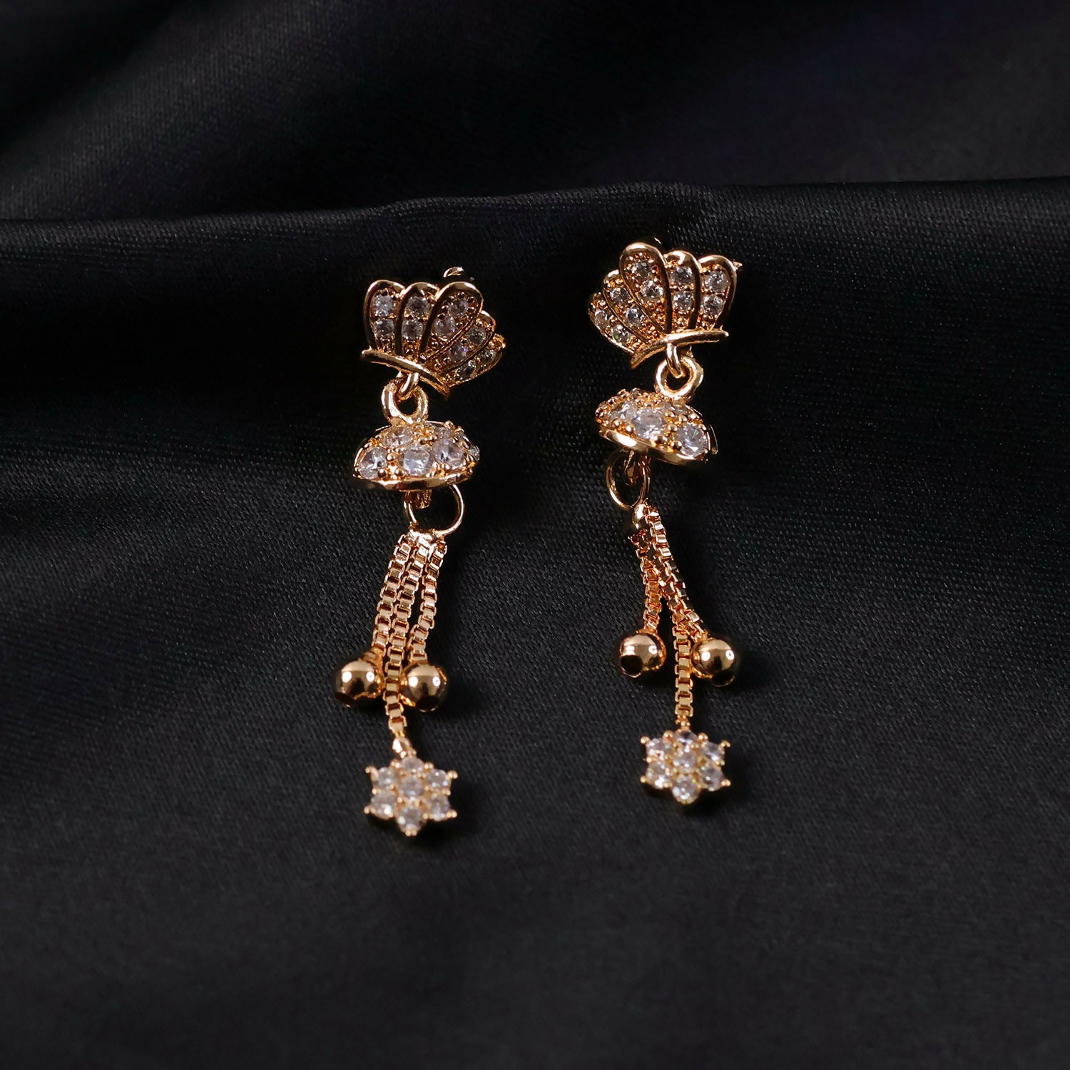 Detailed look at the crystal-embellished crown design on gold finish drop earrings