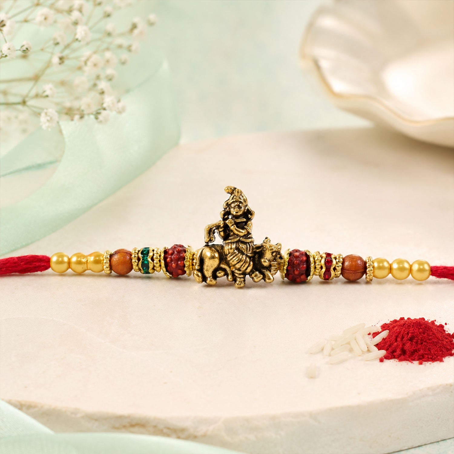 Bal Krishna Golden Devotional Rakhi with Idol Centre, Red Beads and Pearl Accents